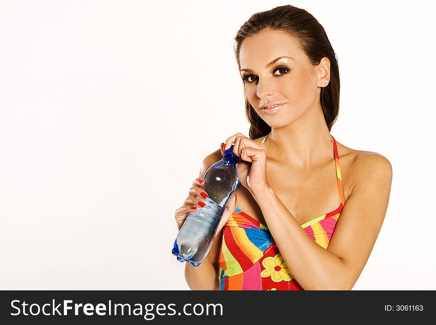 A beautiful brunette girl wearing colorful dress holding a big bottle of mineral water on white background. A beautiful brunette girl wearing colorful dress holding a big bottle of mineral water on white background