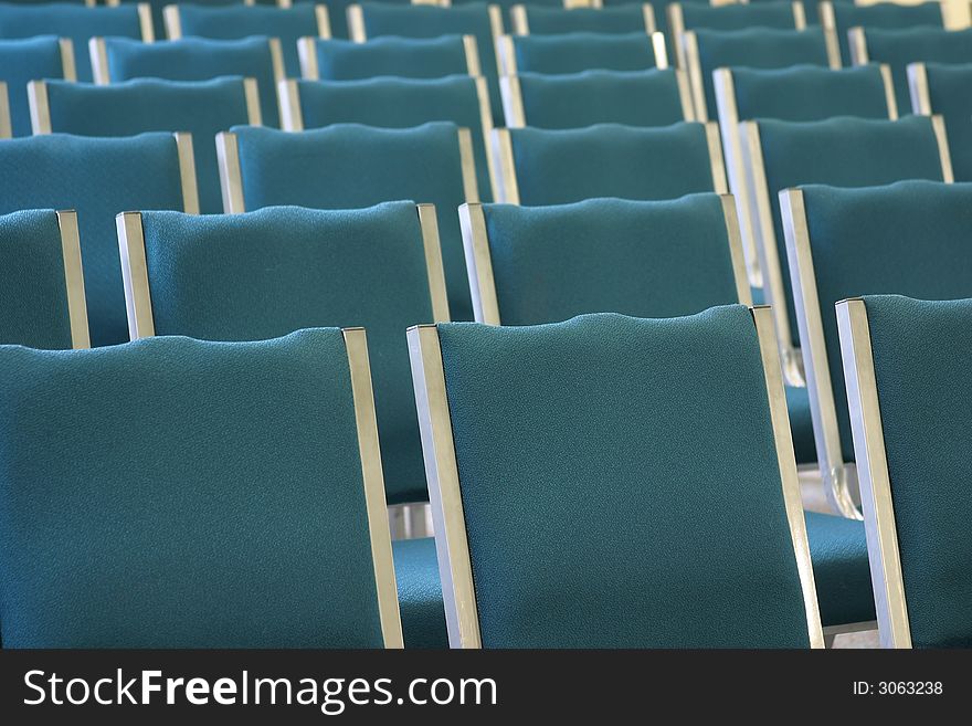 Rows of empty chair backs in large room.