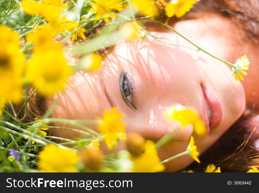 Beautiful girl laying on a field among fresh grass & yellow flowers. Beautiful girl laying on a field among fresh grass & yellow flowers.