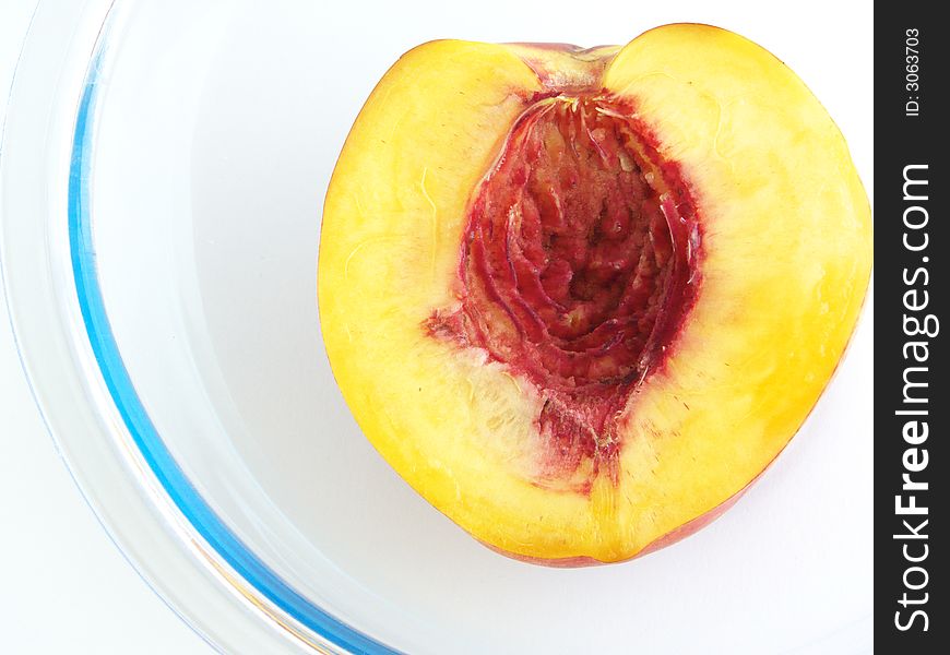 Half peach rests in a glass vases. Isolated on 
a white background.