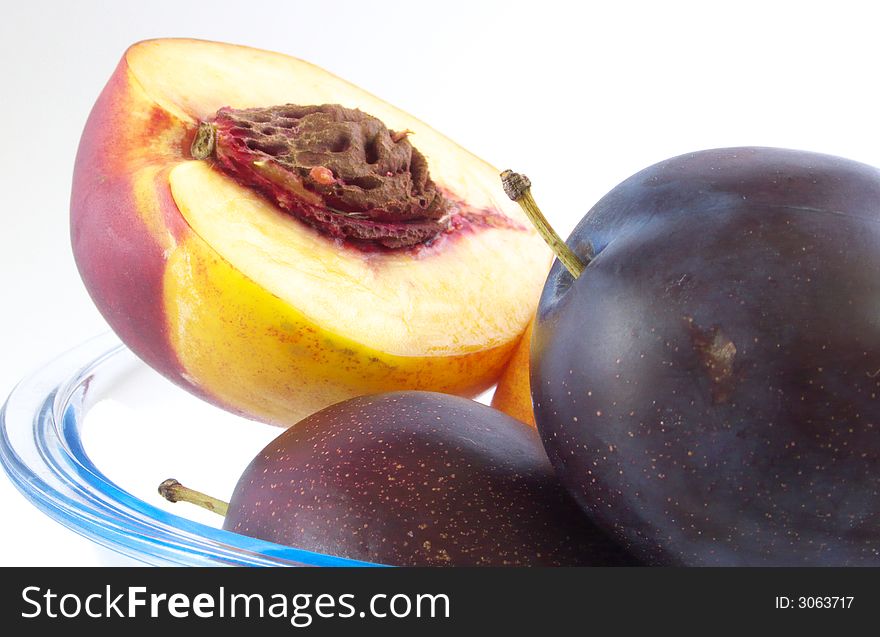 Pieces plums and peaches are in glass vases. Isolated on a white background. Pieces plums and peaches are in glass vases. Isolated on a white background.