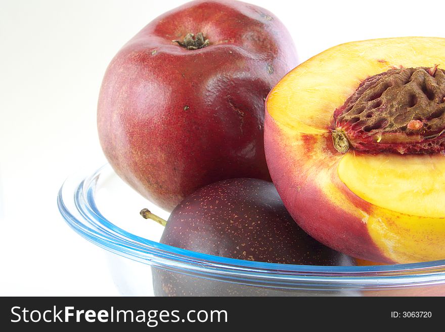 Red pear, peaches and plums pieces are in glass vases. Isolated on a white background. Red pear, peaches and plums pieces are in glass vases. Isolated on a white background.