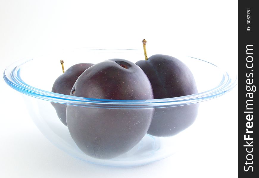 Three Plums lie in a glass vases. Isolated on a white background. Three Plums lie in a glass vases. Isolated on a white background.