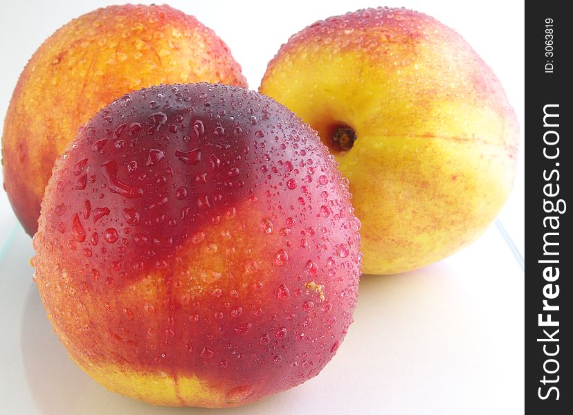 Three peach isolated on a white background. They dew drops.