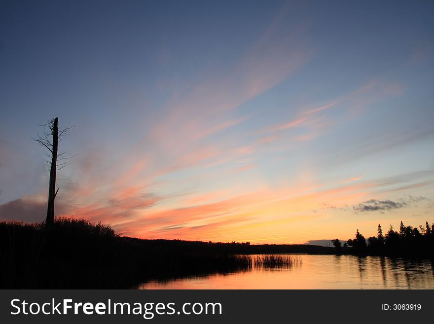 Wide angle sunset over lake with dead tree. Wide angle sunset over lake with dead tree.