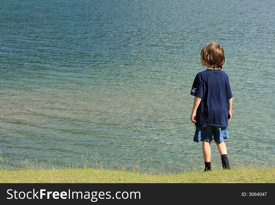 Portrait of a young boy standing on shore above a lake. Portrait of a young boy standing on shore above a lake.