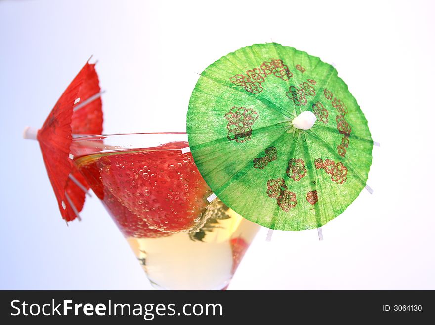 Strawberries in a glass of sparkling apple juice with cocktain umbrellas. Strawberries in a glass of sparkling apple juice with cocktain umbrellas