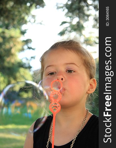 Young girl blowing bubbles with a small wand. Young girl blowing bubbles with a small wand.