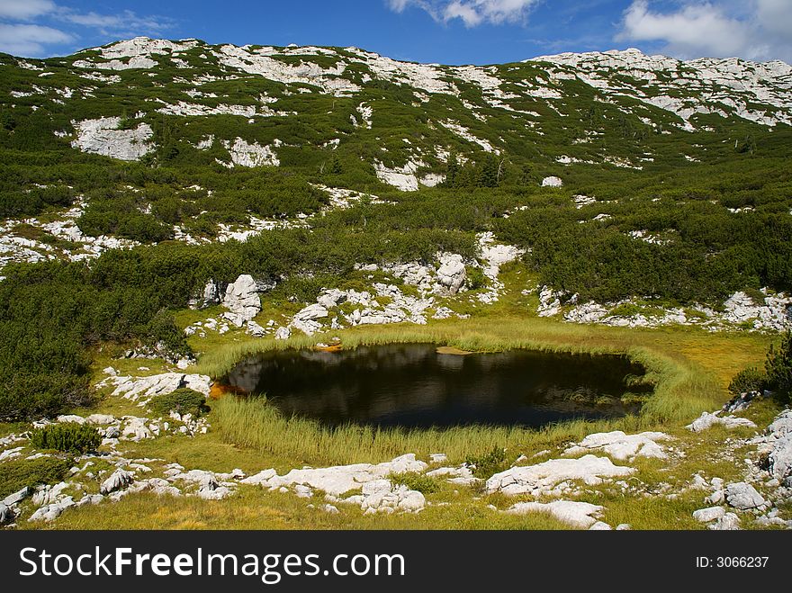 Small clean alpine lake in sunny weather.