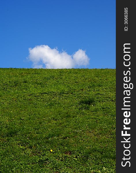 Green meadow and blue sky with single white cloud. Green meadow and blue sky with single white cloud.