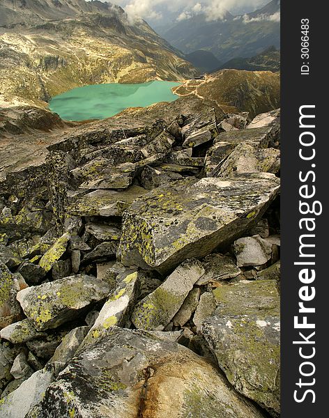 Blue mountain lake with stones in foreground.