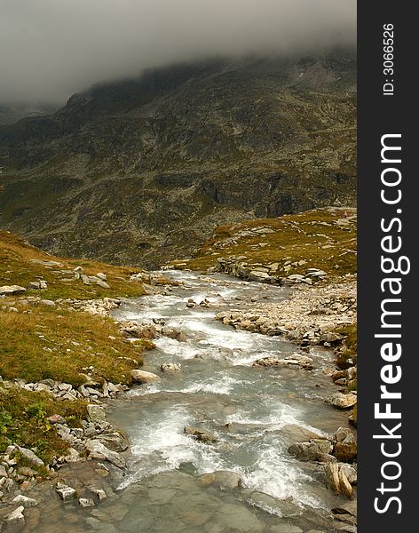 Alpine mountain stream with rainy mist.