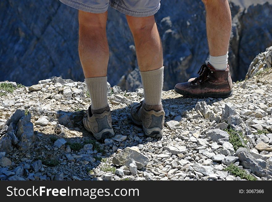 Two hikers resting along rocky ridge on a trail. Two hikers resting along rocky ridge on a trail