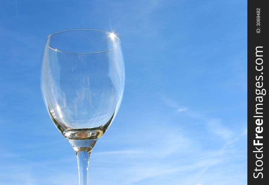 Empty wineglass on sky background