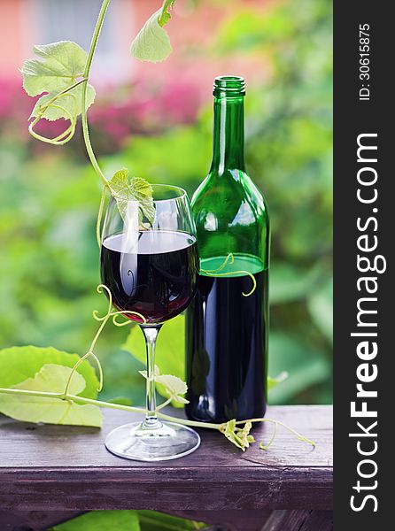 Bottle and glass with red wine in vineyard.