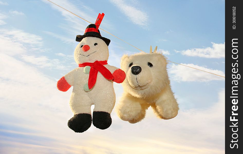 Toy polar bear and snowman hanging on a rope and drying off after washing on the background of a gentle spring sky. Toy polar bear and snowman hanging on a rope and drying off after washing on the background of a gentle spring sky