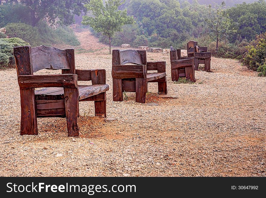 Benches made â€‹â€‹of thick rough-treated wood stand in a row in a recreation area in the park. Benches made â€‹â€‹of thick rough-treated wood stand in a row in a recreation area in the park