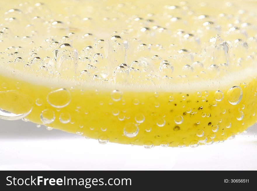 Bubbles on a lemon slice in soda water. Bubbles on a lemon slice in soda water