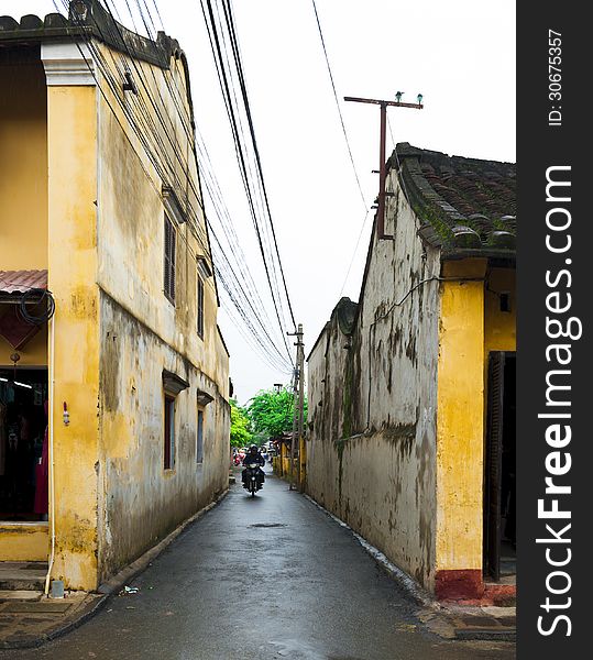 Man driving motorcycle on small alley in Hoi an, Vietnam. Man driving motorcycle on small alley in Hoi an, Vietnam