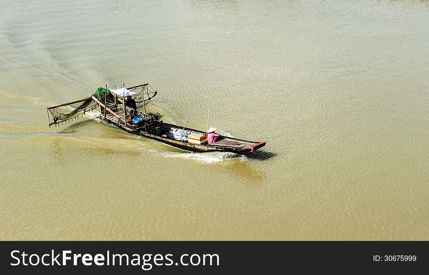 Fishing boat on the river with woman wearing conical hat