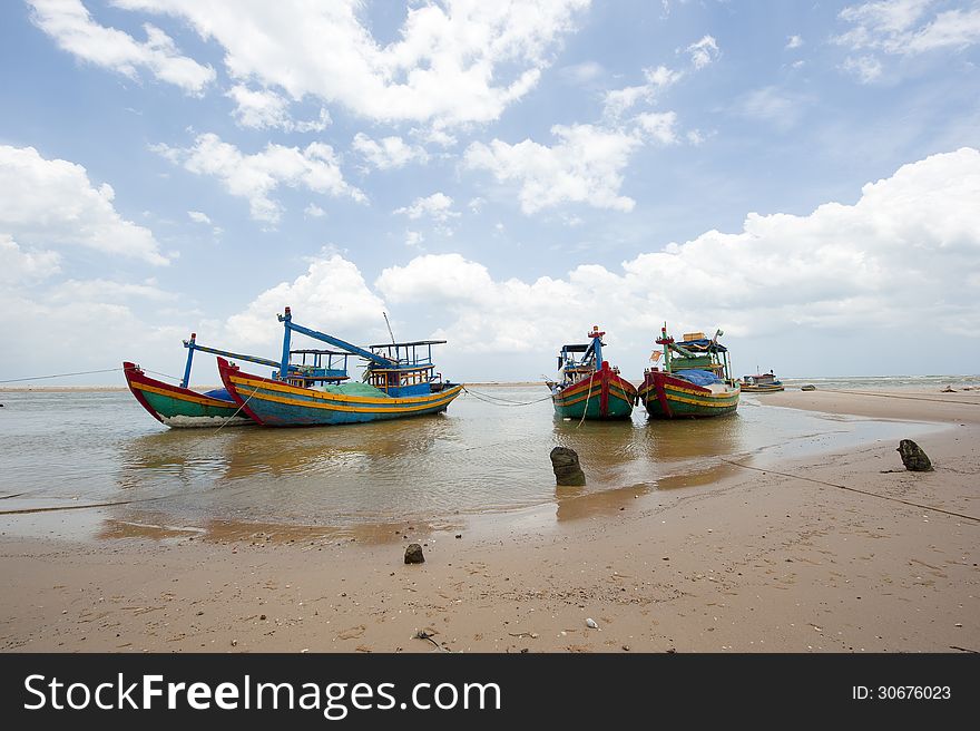 The fishing boats anchored near the seaside with cloudy sky at background