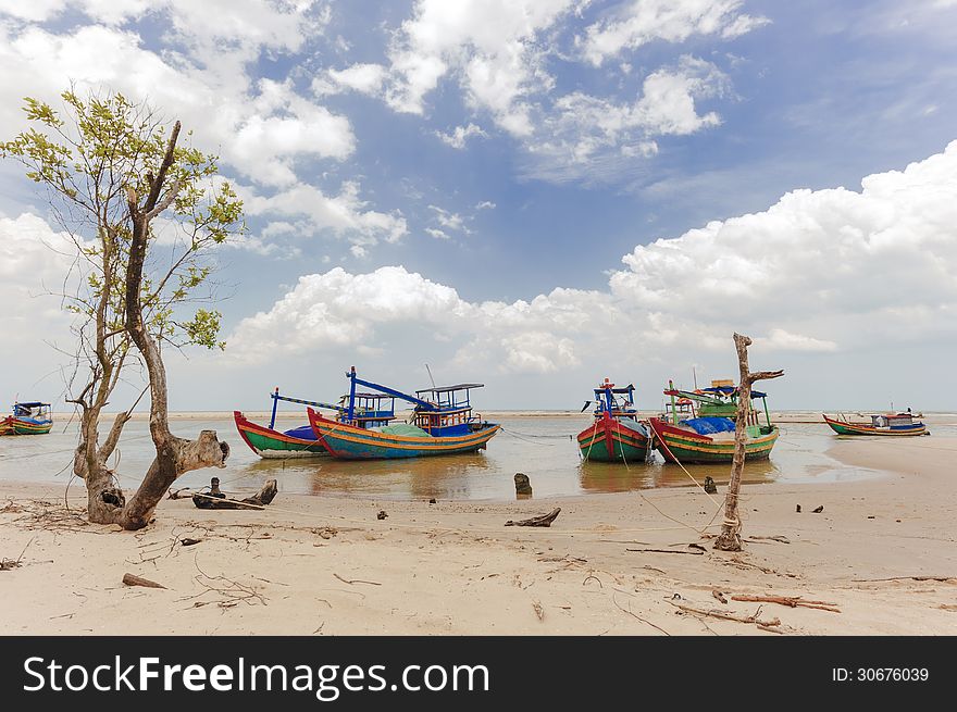 The fishing boats anchored near the seaside with cloudy sky at background