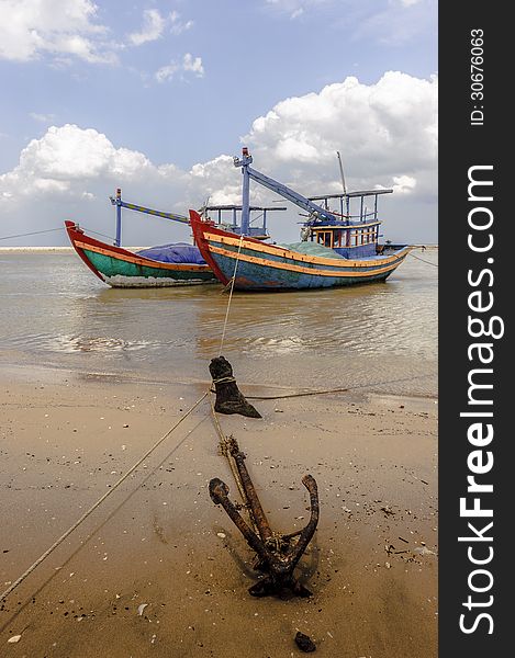 The fishing boats and the anchor at the seaside with cloudy sky at background. The fishing boats and the anchor at the seaside with cloudy sky at background