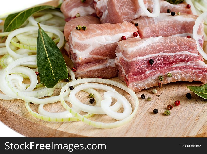 Raw meat on wooden cutting board with onion and pepper