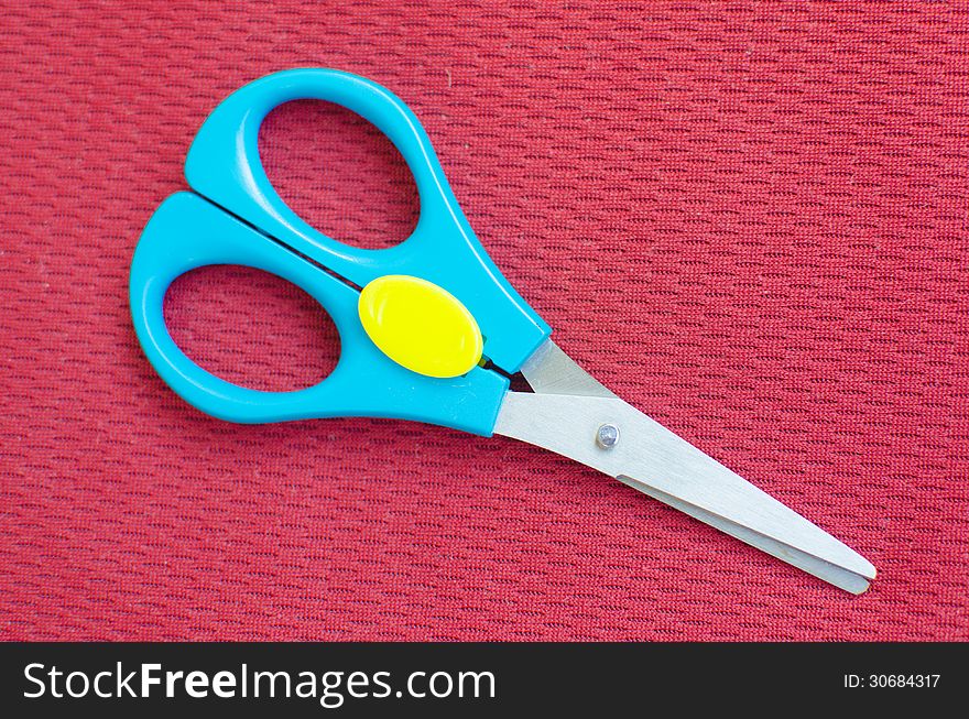 Colorful scissor on red textile background