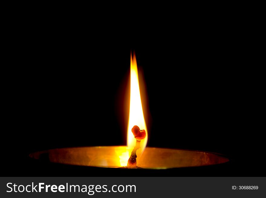 Flame of a Diya isolated on dark black background.