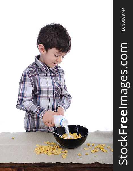 Preschool boy is preparing is breakfast of corn flakes and milk. Preschool boy is preparing is breakfast of corn flakes and milk