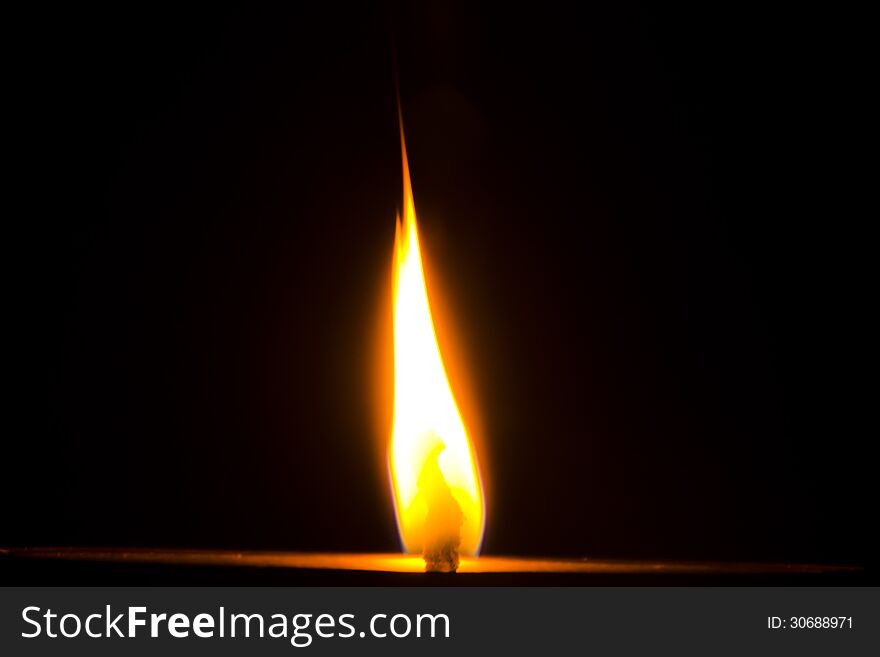 Flame of a Diya on dark black background.