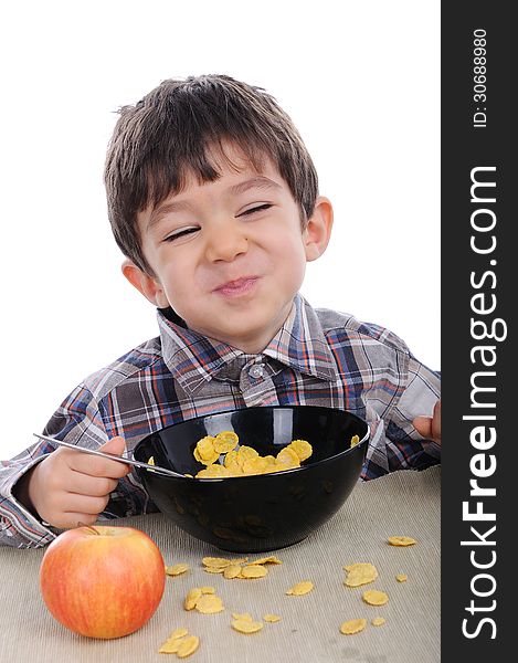 White cute boy is eating corn flakes for breakfast.