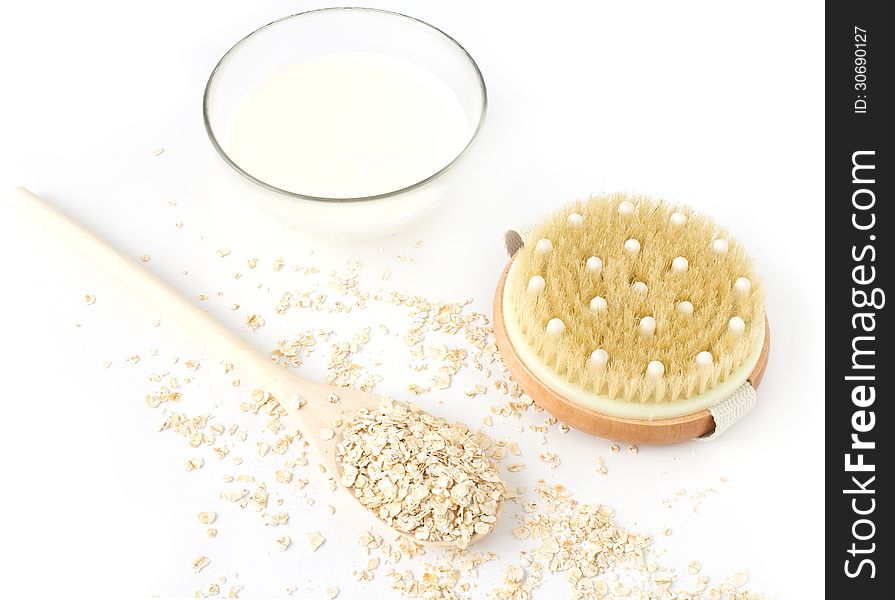 Oatmeal in the wooden spoon and milk on white background