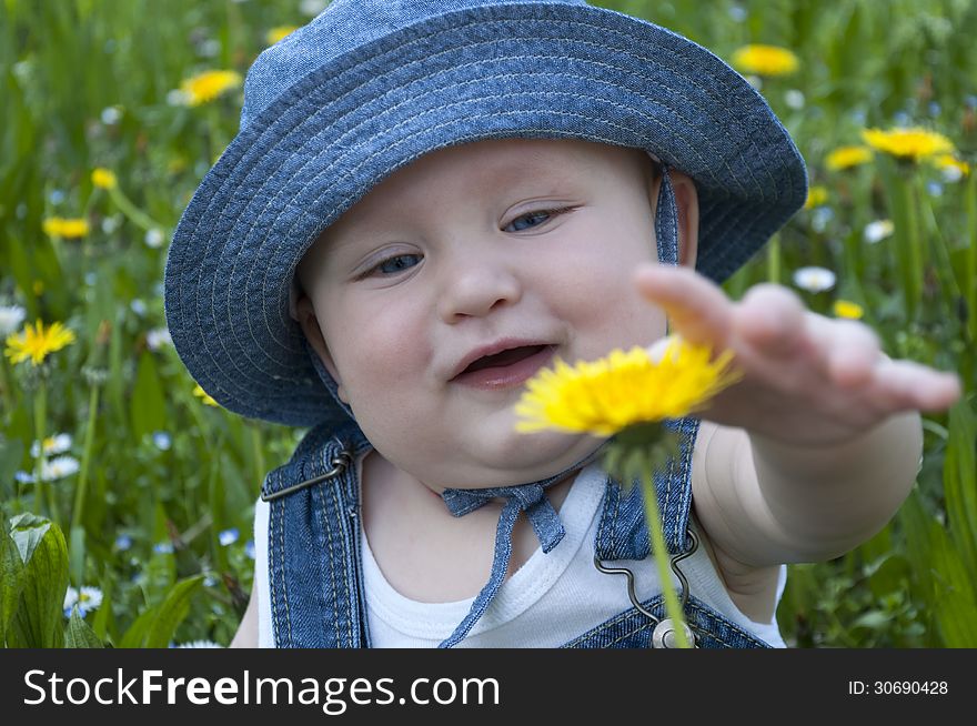 Little boy in a hat taking a flower