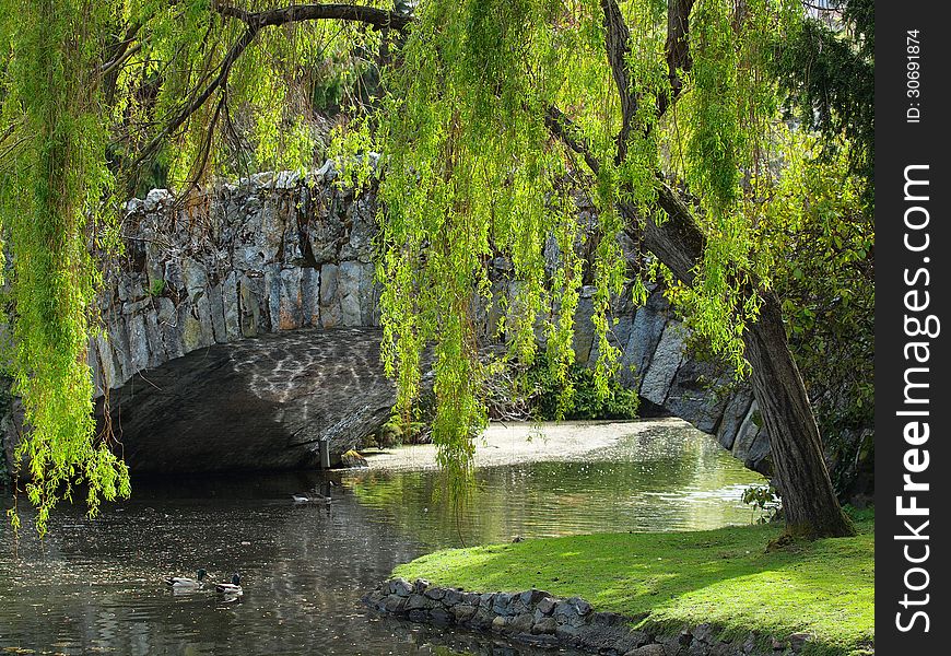 Tranquil scene with antique stone bridge over the pond in the park. Tranquil scene with antique stone bridge over the pond in the park