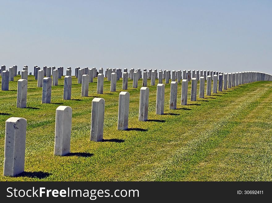 Gravestones of a large cemetary on a grassy hillside.