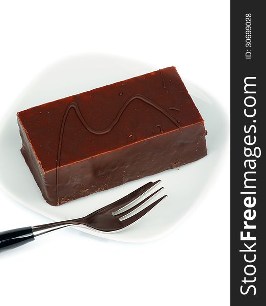 Creamy Mousse Cake Glazed with Dark Chocolate on White Plate with Dessert Fork closeup