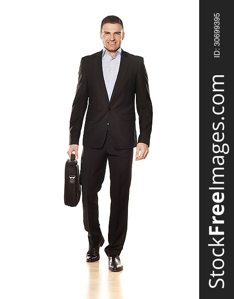 Studio shot of attractive smiling young businessman walking with a laptop bag. Studio shot of attractive smiling young businessman walking with a laptop bag