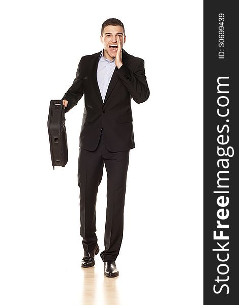 Attractive young businessman with a laptop bag, shouting with his hand next to his mouth. Attractive young businessman with a laptop bag, shouting with his hand next to his mouth