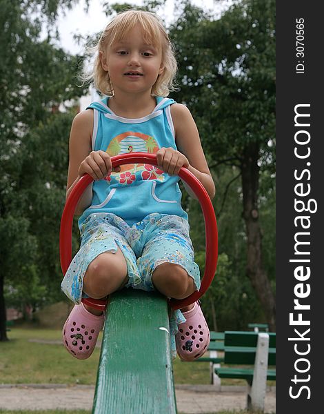 Pretty childhood girl swaying on the balance swing