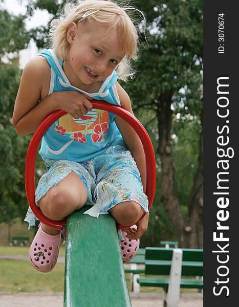 Pretty childhood girl swaying on the balance swing