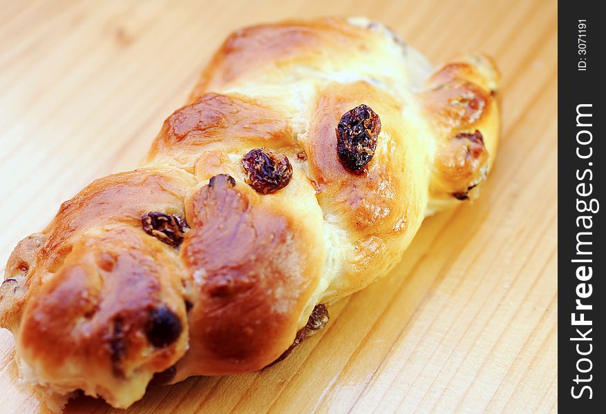 Baked yeast twist with raisins on wooden table