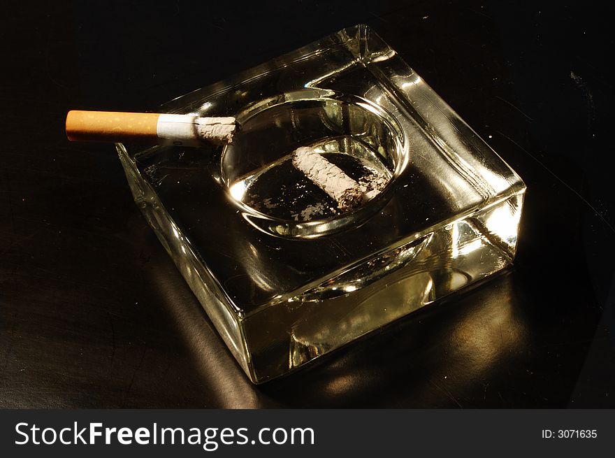 A cigarette in the ashtray. A cigarette in the ashtray