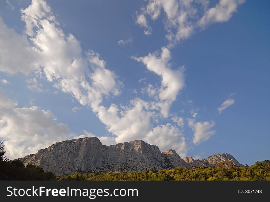 Mountain landscape with white clouds in  dark blue sky. Mountain landscape with white clouds in  dark blue sky