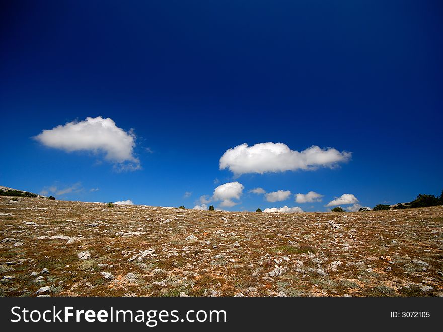 Mountain landscape with white clouds in  dark blue sky