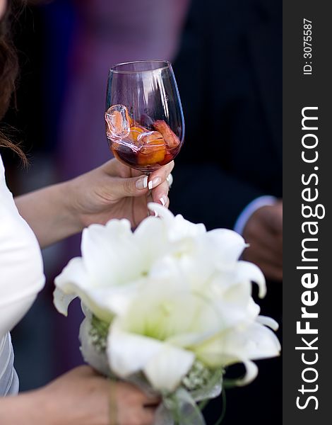 Bride holding a glass with Red-Wine-Cooler. Closeup. Focus on glass. Bride holding a glass with Red-Wine-Cooler. Closeup. Focus on glass.