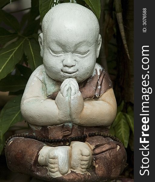 Sculpture of an Asian praying child making a wai at a Buddhist temple in Thailand. Sculpture of an Asian praying child making a wai at a Buddhist temple in Thailand