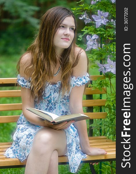 Beautiful girl reading and dreaming in summer