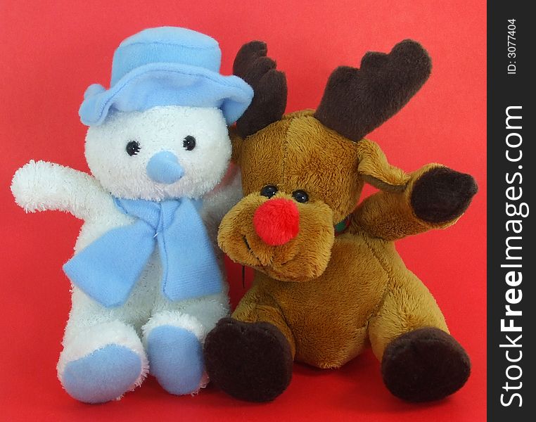 A cute plush snowman and reindeer on a red background. A cute plush snowman and reindeer on a red background.